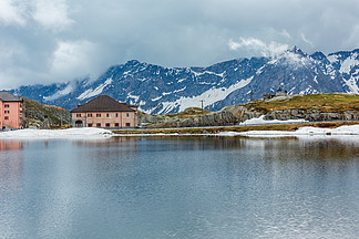 春天的阿尔卑斯山湖泊拉戈德拉广场和亚历山大苏沃罗纪念碑在远处（瑞士，帕索德尔圣戈塔多）。该纪念碑是 Dmitry N. Tugarinov 1999 年的作品。