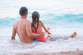 一家人在海浪中游泳。夏季家庭度假。父亲和他的女儿享受海滩假期