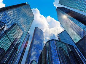 市中心企业商务区建筑理念：玻璃反射办公楼摩天大楼与云彩和阳光的蓝天映衬