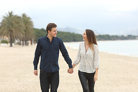 一对热恋中的情侣在冬天在沙滩上散步和相望的正面图