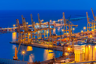 西班牙加泰罗尼亚巴塞罗那，夜间从蒙锥克山照亮的海运港口和集装箱码头的鸟瞰图。
