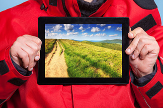 男性手拿着 <i>ipad</i> 与山的照片的特写镜头。显示屏幕平板触摸板梦想冒险之旅的人旅行者。技术和旅行。