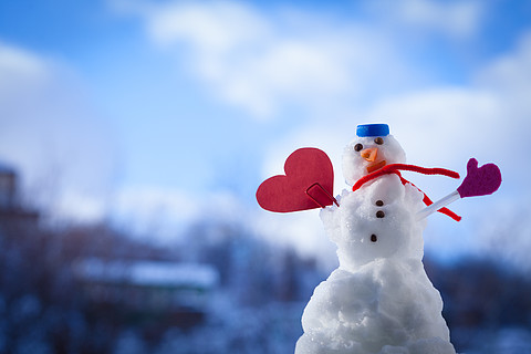 小快乐圣诞雪人在蓝色螺旋顶部作为帽子红围巾和夹在户外的红色心形