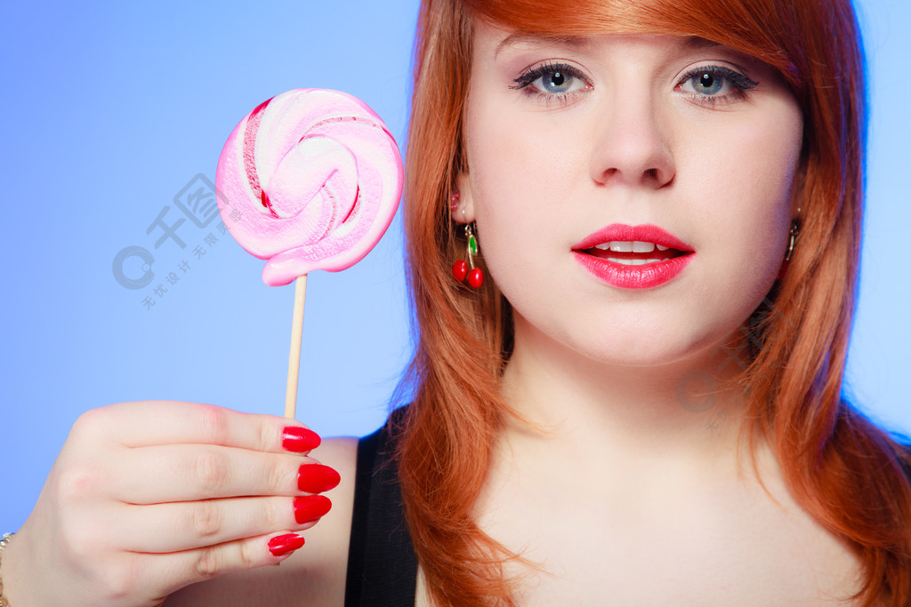 性感的年轻女子拿着糖果redhair女孩在紫罗兰色上吃甜棒棒糖工作室