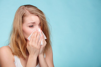 流感感冒或过敏症状。生病的女人女孩在蓝色的纸巾上打<i>喷</i>嚏。卫生保健。