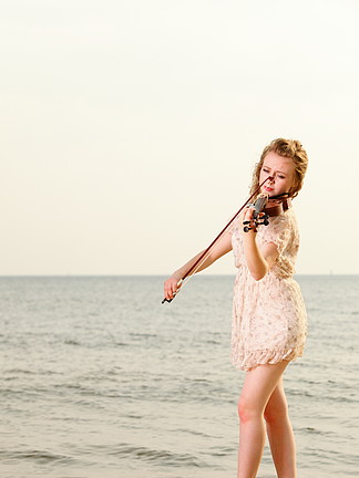 海滩上拉小提琴的金发女孩<i>音</i><i>乐</i>爱好者。热爱<i>音</i><i>乐</i>概念。