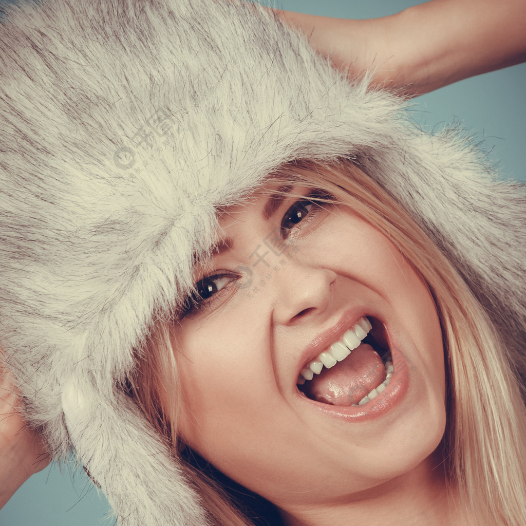 快乐的金发女人在冬天温暖毛茸茸的帽子在俄罗斯风格