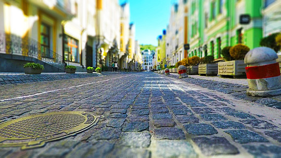 老城街道铺有石板路,汽车模糊,行人复古色彩,具有选择性聚焦效果