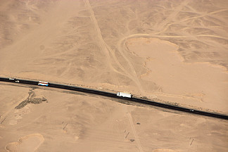 查<i>看</i>从飞机在沙漠途中的窗口。在沙漠中沿公路行驶的公共汽车鸟瞰图。沙漠公路鸟瞰图。公路旅行旅行冒险。公路穿越沙地。沙漠公路鸟瞰图。公路旅行旅行冒险
