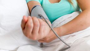 生病的女人躺在床上测量血压的特写照片。病人躺在床上测量血压的特写图像