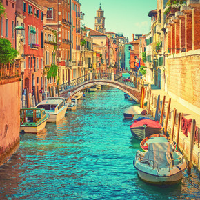 在阳光明媚的夏日，意大利威尼斯，停泊着摩托艇的运河。复古风格色调