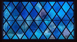 天主教堂彩色玻璃<i>窗</i>彩色灯光下蓝色菱形<i>窗</i>格的细节。美国天主教堂彩色玻璃<i>窗</i>中的蓝色钻石<i>窗</i>格