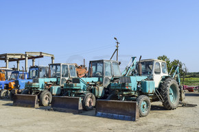 俄罗斯，Temryuk-2015 年 7 月 15 日： 拖拉机。推土机和平地机。带挖土桶的拖拉机。这张照片是在 Temryuk 郊区的一个农村车库里的一个拖拉机停车场拍的。 拖拉机有一个挖土用的桶。