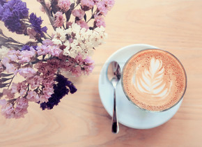 一杯拿铁或卡布奇诺咖啡和具有复古过滤效果的鲜花