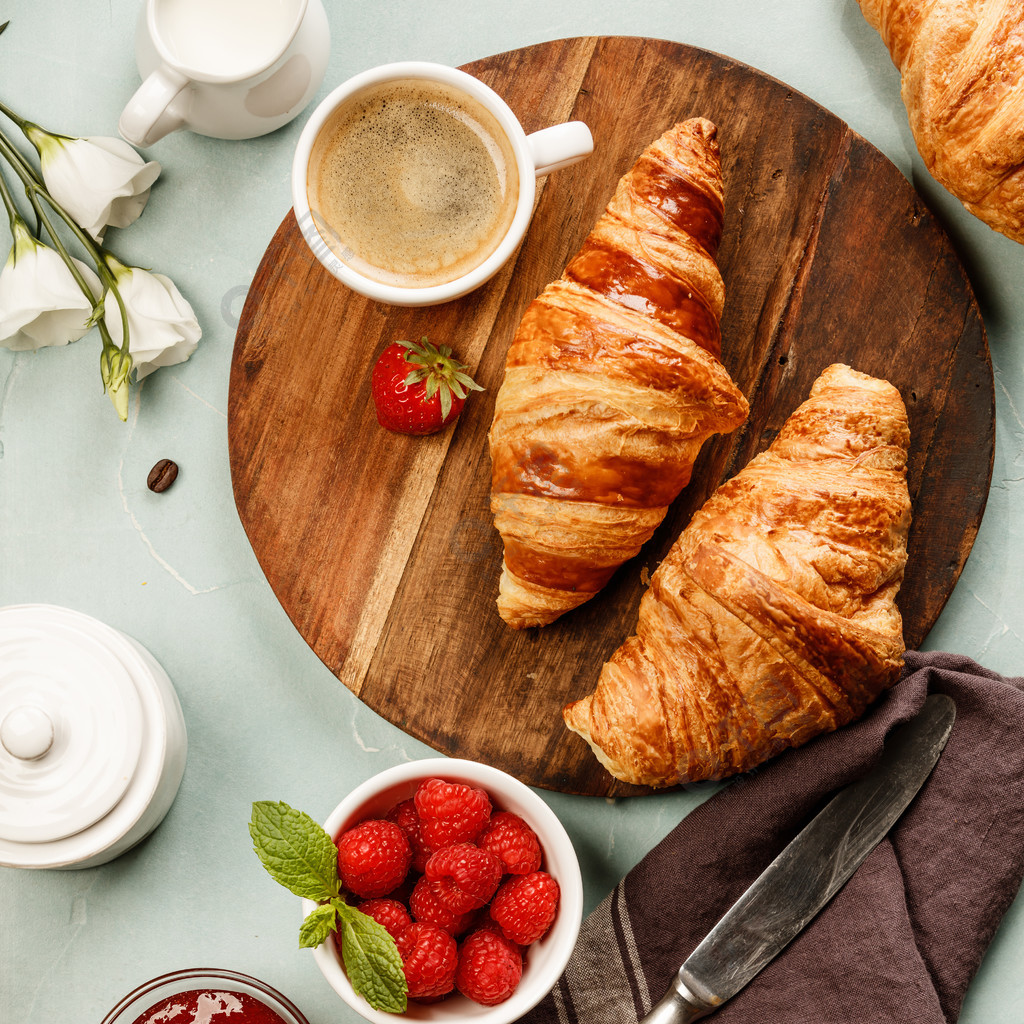 从顶视图捕获的欧陆式早餐平躺咖啡橙汁羊角面包果酱浆果牛奶和鲜花