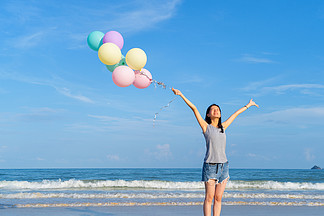 泰国普吉岛中午在海洋或自然海户外度假时，快乐的亚洲女性在海滩上拿着彩色气球