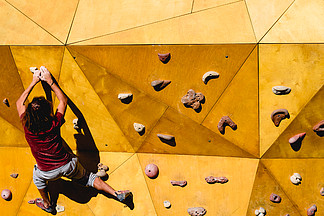运动员试图用他的手和腿的力量<i>到</i>达攀岩墙的顶部。