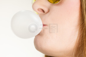 女人休闲风格的少女太阳镜用口香糖特写做泡泡。青春风采。用口香糖做泡泡的女人