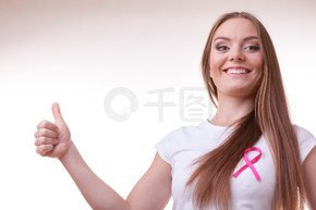 医疗保健、医学和乳腺癌意识概念。心满意足的年轻女子，胸前有粉红色的癌症丝带，做出竖起大拇指的手势。女人胸前粉色癌症丝带竖起大拇指