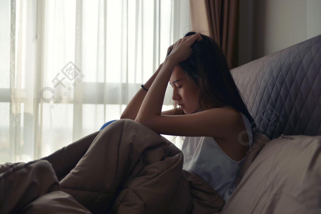 坐在床上患有抑郁症的亚洲女人