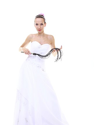 婚礼当天。身穿白色连衣裙、黑色皮革鞭打鞭子的全长年轻迷人新娘与白色背景隔离