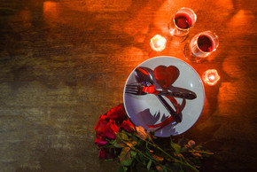 情人节晚餐浪漫爱情概念/浪漫餐桌布置，盘子上用叉勺装饰，餐桌晚餐夜灯顶视图上配有烛光的一对香槟玻璃酒玫瑰
