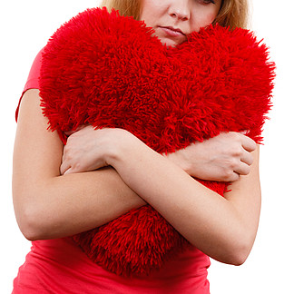 女人悲伤的女孩拥抱红色的心爱象征