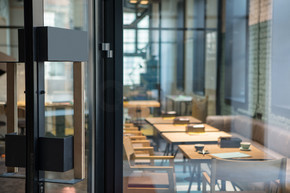 咖啡厅前木玻璃门上的现代门把手。现代风格的室内设计。餐厅的门打开了。咖啡厅前木玻璃门上的现代门把手。