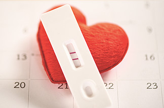 怀孕测试孕妇概念/阳性结果两行计划婴儿母亲和医疗保健以及日历背景上的红心