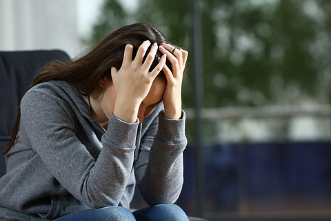 悲傷的女人獨自坐在家裡的沙發上抱怨