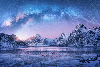 挪威罗弗敦群岛冬季夜间冰冻海岸和雪山上的银河。与蓝色星空、 水、 冰、 白雪皑皑的岩石、 银河系的北极景观。太空和银河