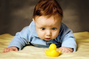 一个孩子惊讶地考虑一只玩具鸭。