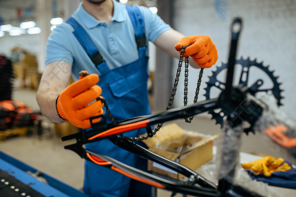 自行车厂工人在装配线上拿着自行车链穿制服的男性机械师在车间工业
