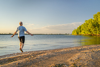 活跃的老人正在科罗拉多州北部博伊德湖州立公园的湖滩上跳一根沉重的健身跳绳