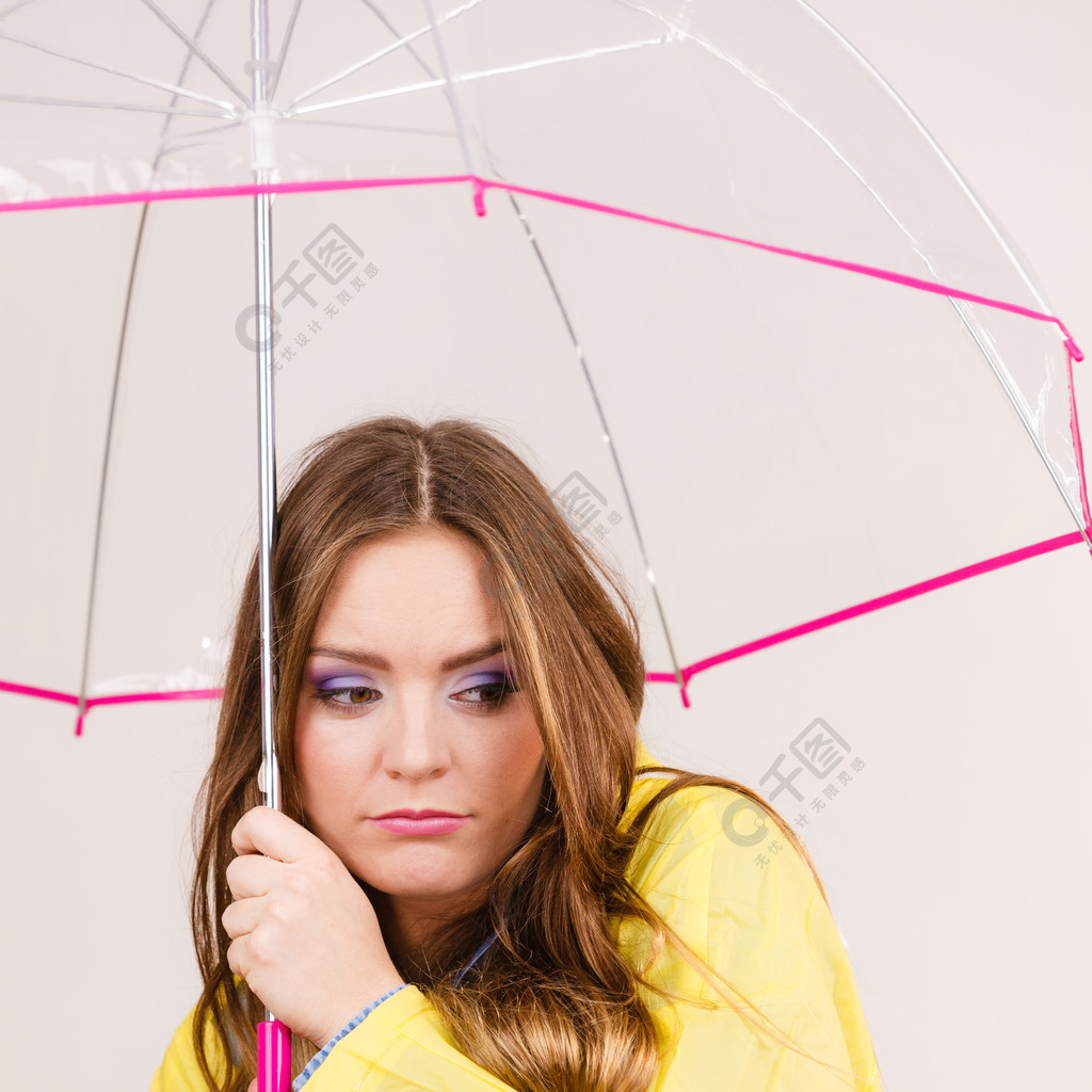 女人多雨的女孩穿著防水黃色外套站在透明的雨傘下看起來悲傷不快樂