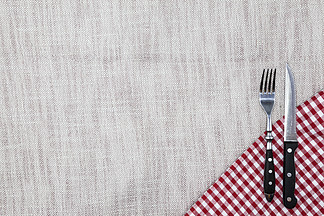 创建餐厅菜单的背景。亚麻桌布叉刀放在明亮的格子布上。用于为牛排餐厅创建菜单