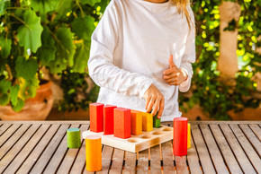 女孩放置一个几何蒙台梭利拼图的颜色，一个用木头和可持续和生态颜色制成的玩具。