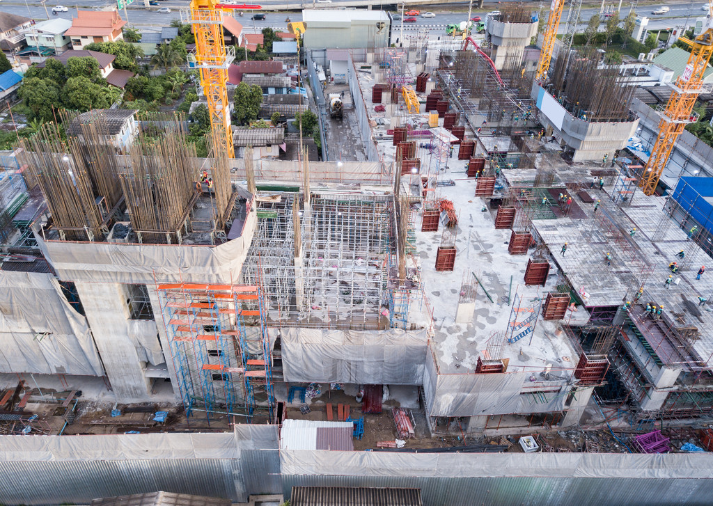 繁忙的工業建築工地工人用起重機工作的鳥瞰圖中午開發高層建築的