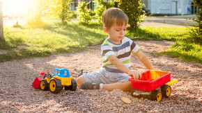 可爱的小男孩在游乐场上玩玩具的特写照片。孩子玩卡车、挖掘机和拖车。他假装是一名建筑工人或司机。可爱的小男孩在游乐场上玩玩具的特写镜头。孩子玩卡车、挖掘机和拖车。他假装是一个建筑商或司机