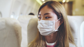 乘坐商用飞机旅行时戴口罩的旅客。冠状病毒病或 COVID 19 大流行病爆发对旅游业和航空业的影响的概念。