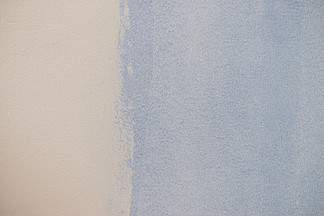 白墙上的油漆色板。淡蓝色复古色与光的比较。纹理、图案和彩色背景概念。白墙上的蓝色油漆样本