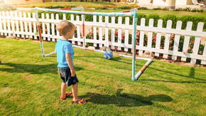 快乐微笑的蹒跚学步的男孩在公园足球场上进球的照片。活跃的孩子们做运动。快乐微笑的蹒跚学步的男孩在公园足球场上进球的形象。活跃的孩子做运动