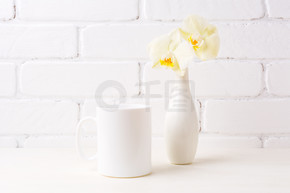 白咖啡杯样机与软黄色兰花在花瓶。空杯子模拟设计推广。 .白咖啡杯样机与花瓶中的软黄兰花