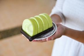 盘子上的蛋糕卷/女士端上绿色蛋糕卷香兰奶油