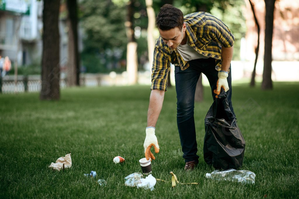 年轻人在公园里的袋子里收集垃圾做志愿者男性清洁森林生态修复生态