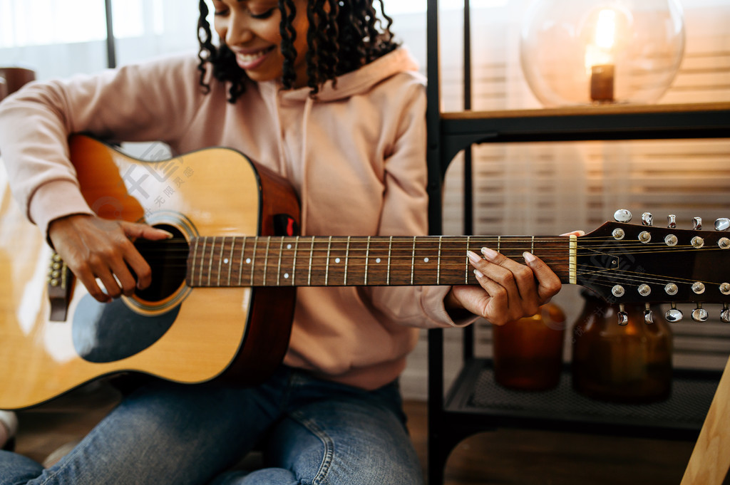 女人坐在地板上在家弹吉他特写镜头漂亮的女士带着乐器在房间里放松