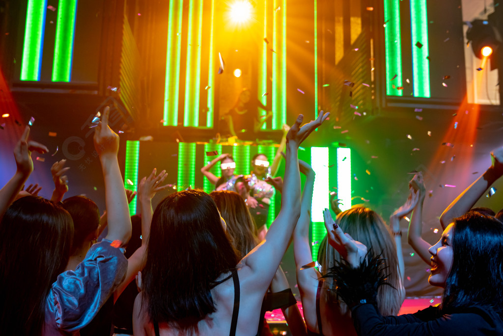 一群人在迪斯科夜总会随着舞台上dj的音乐节拍跳舞新年晚会和夜生活