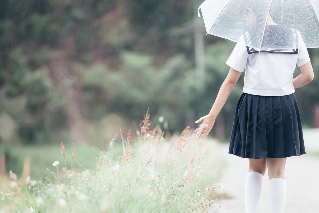 下雨時在自然人行道上撐傘行走的亞洲女學生畫像