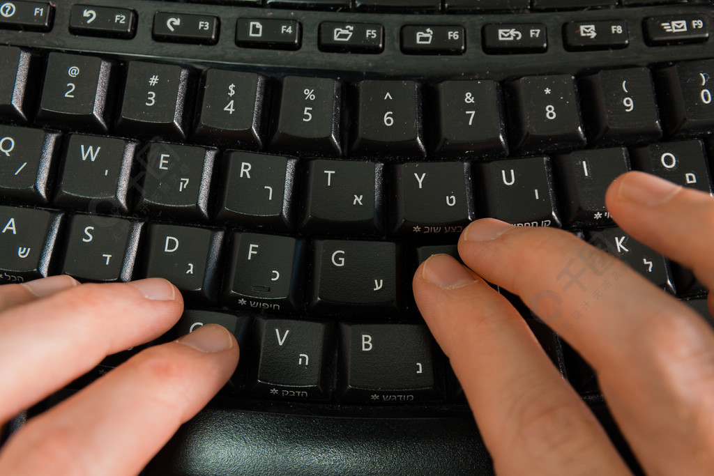 用希伯来语和英语字母在键盘上打字的人无线键盘顶视图