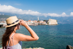 一个年轻漂亮的女人戴着帽子望着黑山布德瓦老城的背影。暑假目的地。一位戴着帽子的年轻美女的背影，望向黑山布德瓦老城